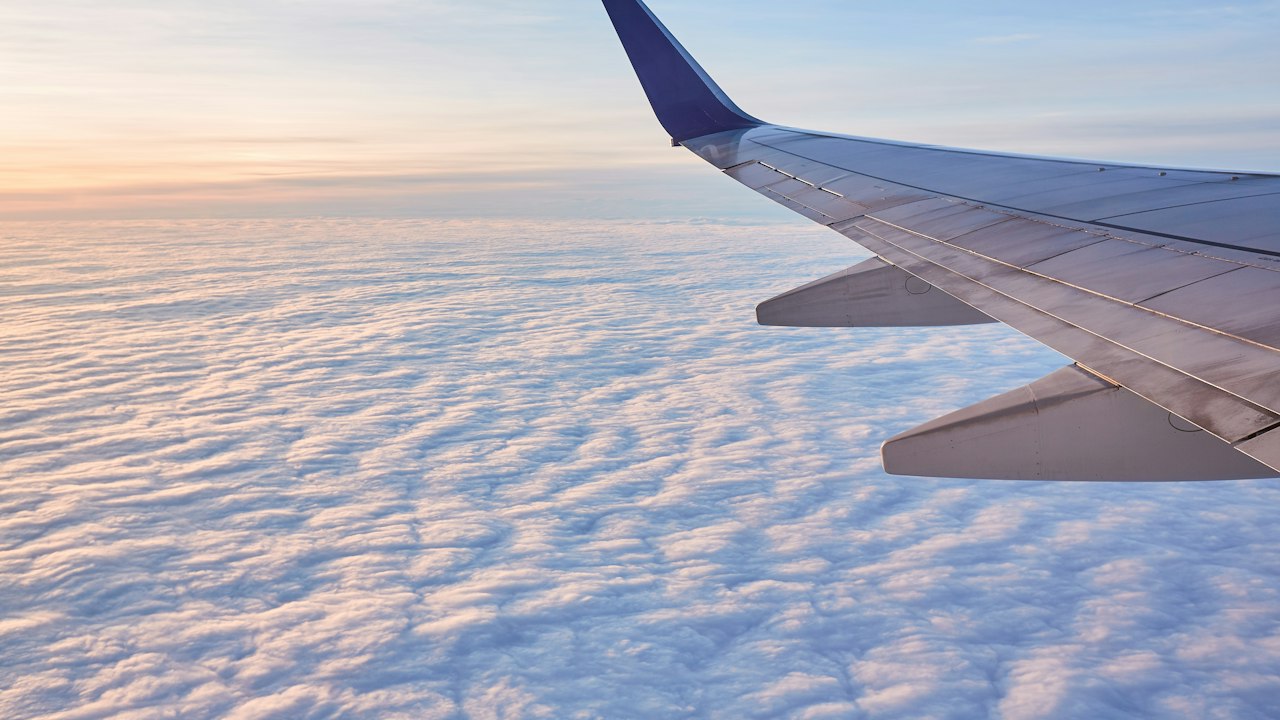 雲の上を飛ぶ旅客機の翼(イメージ)