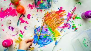 カラフルな絵の具でお絵かきをする子どもの手(イメージ)